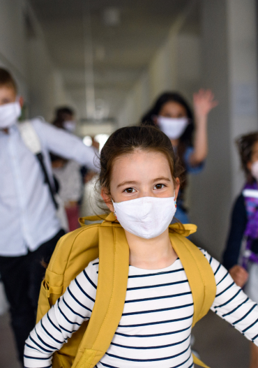 Child wearing a mask and a backpack, smiling expression